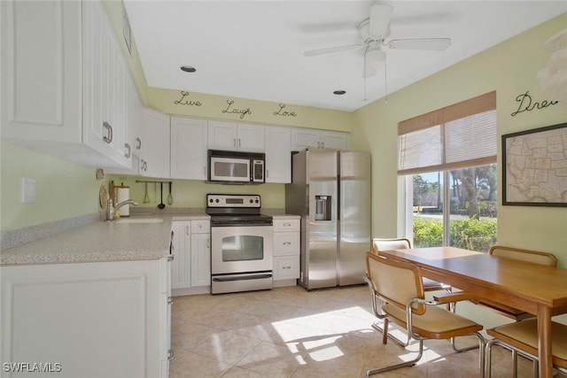 kitchen featuring a ceiling fan, a sink, white cabinetry, stainless steel appliances, and light tile patterned floors