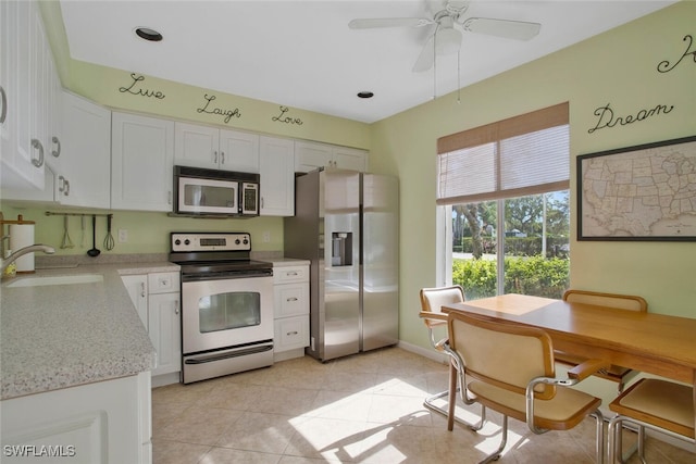 kitchen with ceiling fan, stainless steel appliances, light tile patterned flooring, white cabinetry, and a sink