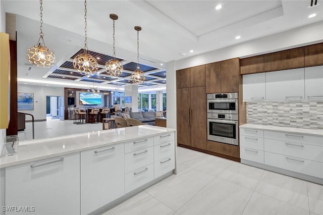 kitchen featuring a raised ceiling, modern cabinets, and an inviting chandelier