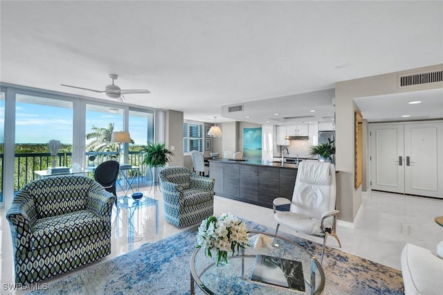 living room with light tile patterned floors, expansive windows, visible vents, and a ceiling fan