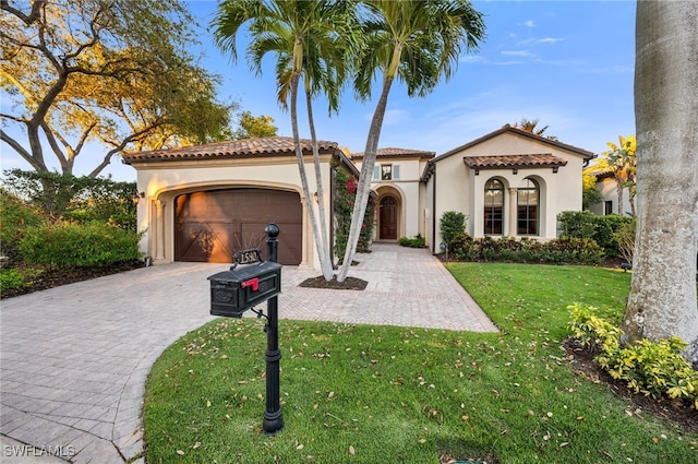 mediterranean / spanish-style home with a tile roof, a front yard, stucco siding, decorative driveway, and a garage