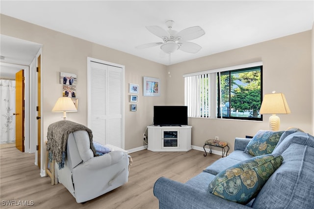 living room with light wood finished floors, ceiling fan, and baseboards