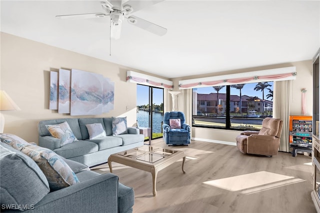 living room with ceiling fan, baseboards, and wood finished floors