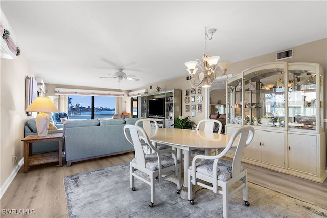 dining room featuring visible vents, light wood-style flooring, ceiling fan with notable chandelier, and baseboards