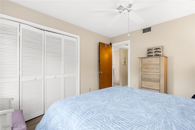 bedroom with dark wood-style flooring, visible vents, a closet, and ceiling fan