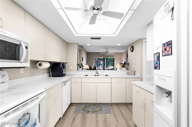 kitchen featuring white appliances, ceiling fan, a sink, light countertops, and light wood-type flooring