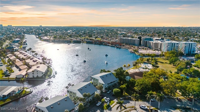 aerial view at dusk featuring a city view and a water view