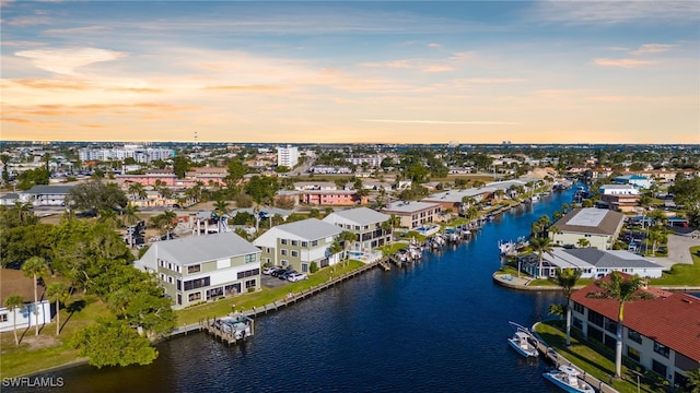 aerial view at dusk with a water view and a residential view