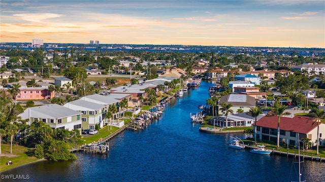 aerial view at dusk featuring a residential view and a water view