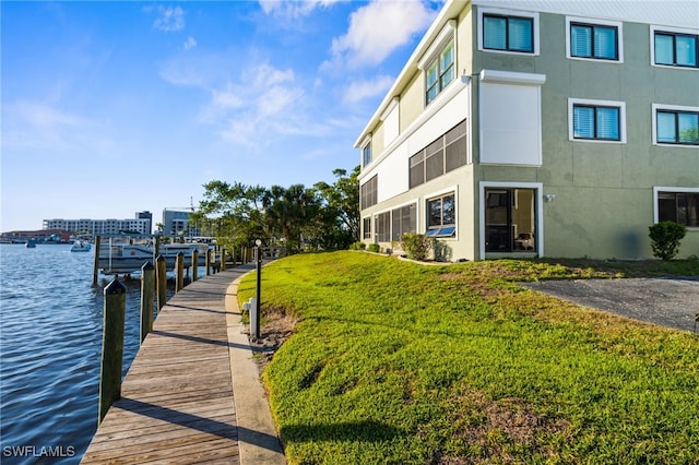 view of dock with a yard and a water view