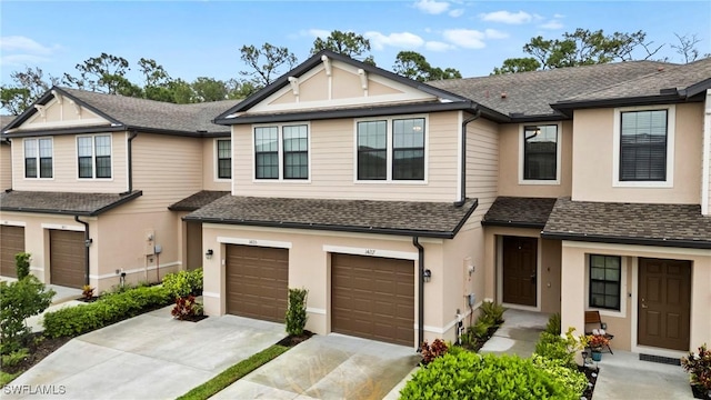 townhome / multi-family property with concrete driveway, roof with shingles, and stucco siding