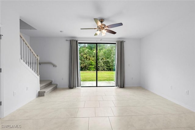 tiled spare room featuring stairway and a ceiling fan