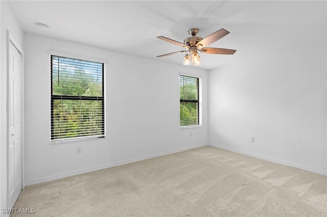 empty room with baseboards, light carpet, and a ceiling fan