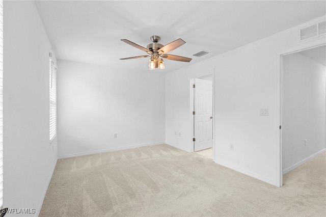 spare room featuring visible vents, light carpet, baseboards, and a ceiling fan