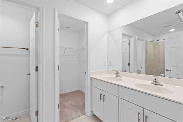 full bathroom featuring a sink, a walk in closet, baseboards, and double vanity