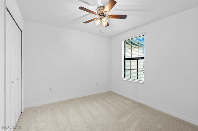 unfurnished bedroom with a ceiling fan, light colored carpet, baseboards, and a closet