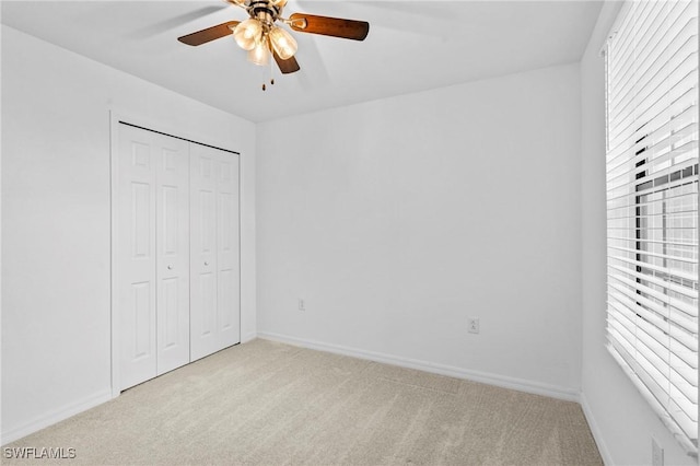 unfurnished bedroom featuring a closet, baseboards, carpet floors, and ceiling fan