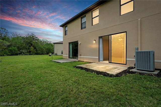 back of house with a patio area, central air condition unit, stucco siding, and a yard