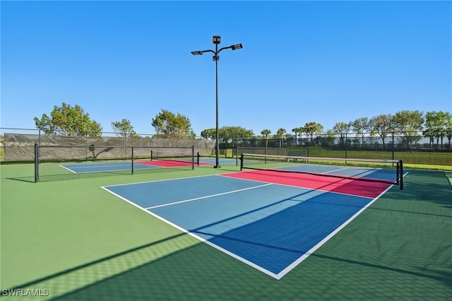 view of tennis court with community basketball court and fence