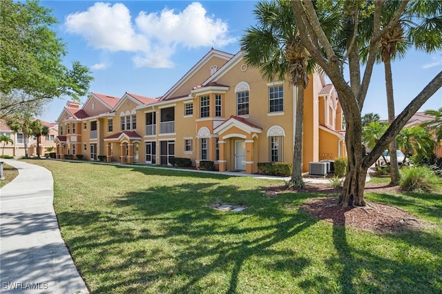 townhome / multi-family property with a residential view, stucco siding, a front lawn, and central AC