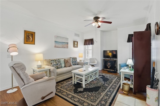 living area featuring visible vents, light wood-style flooring, a ceiling fan, and ornamental molding