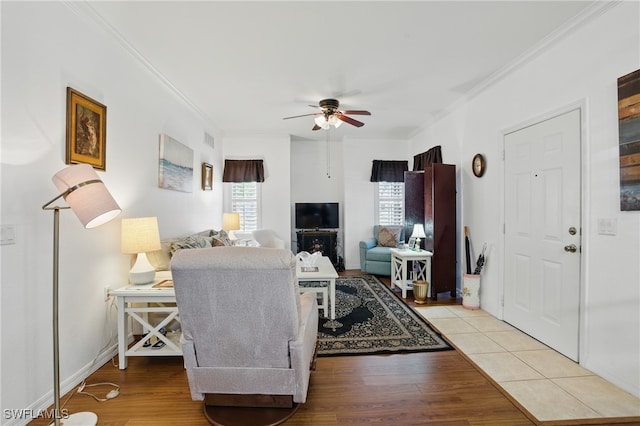 living room with crown molding, wood finished floors, a ceiling fan, and visible vents