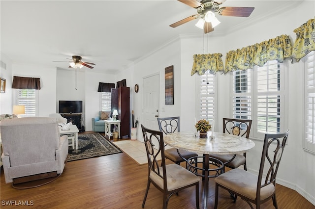 dining space with visible vents, a ceiling fan, wood finished floors, crown molding, and baseboards