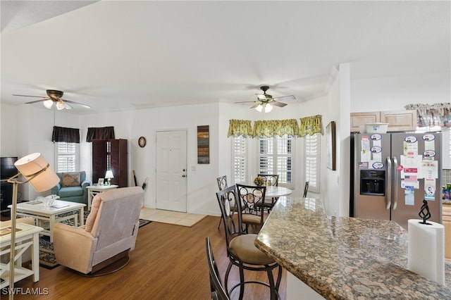 living area with a wealth of natural light, wood finished floors, and a ceiling fan