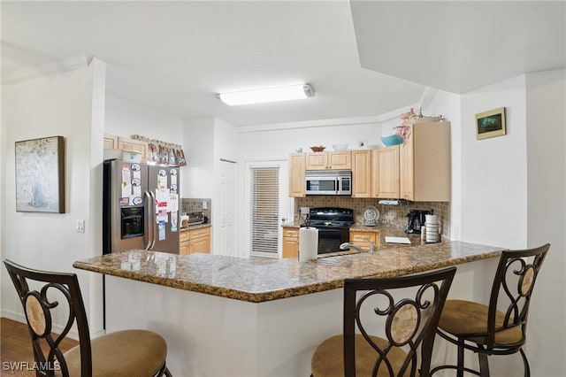 kitchen featuring light brown cabinetry, appliances with stainless steel finishes, tasteful backsplash, and a peninsula