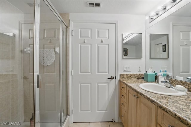 full bathroom featuring tile patterned floors, visible vents, a stall shower, and vanity