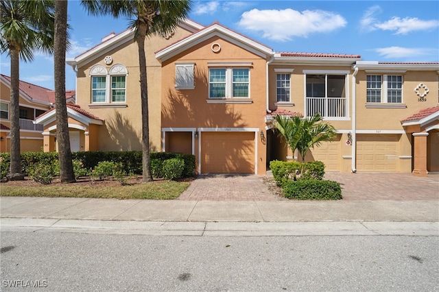 multi unit property featuring stucco siding, driveway, a tile roof, and a garage