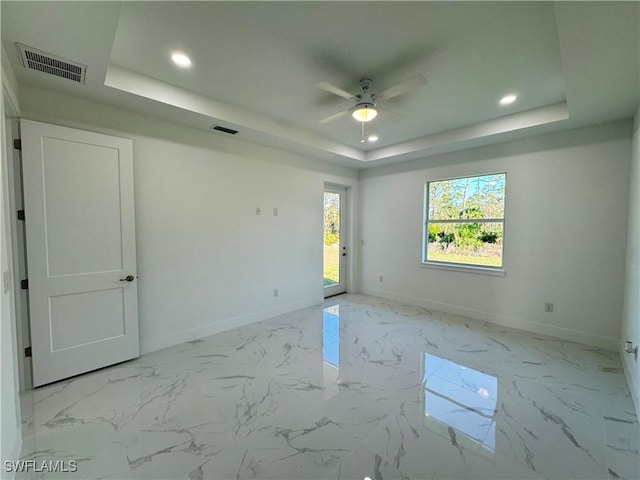 spare room featuring visible vents, marble finish floor, baseboards, and a tray ceiling