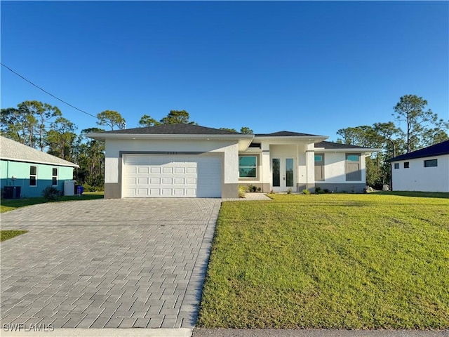 prairie-style home with stucco siding, a front lawn, decorative driveway, french doors, and a garage