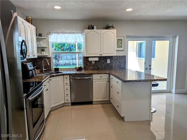 kitchen with decorative backsplash, white cabinetry, a peninsula, and stainless steel appliances