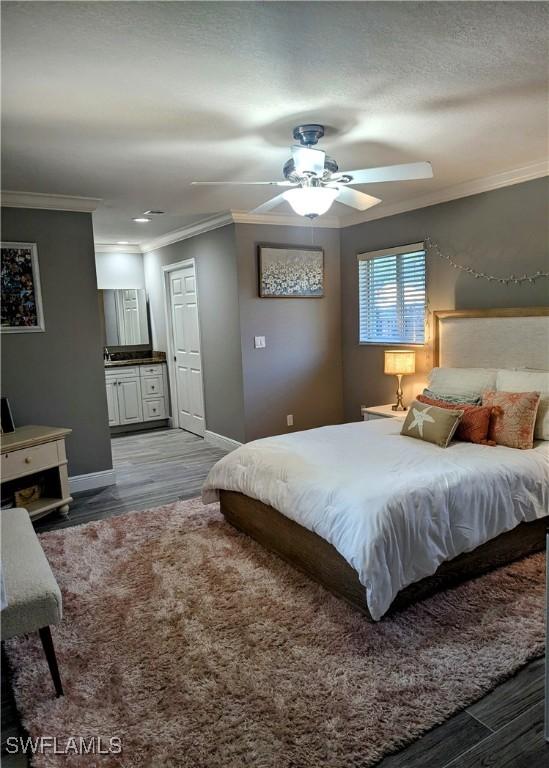 bedroom featuring ensuite bath, crown molding, baseboards, and wood finished floors