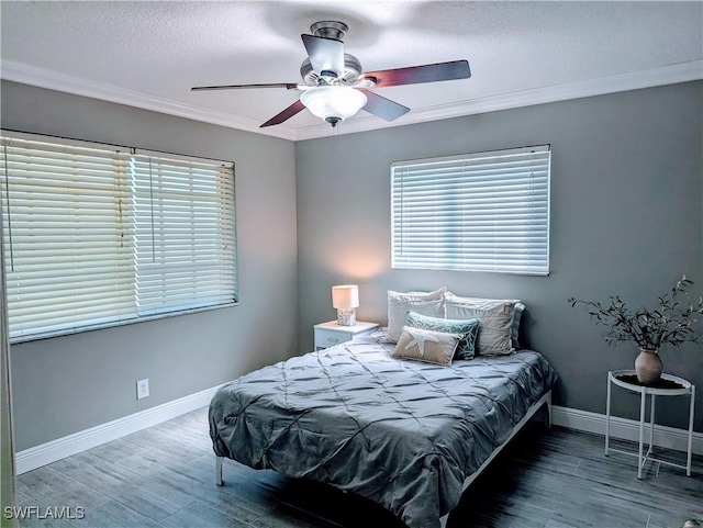 bedroom with a textured ceiling, wood finished floors, crown molding, baseboards, and ceiling fan