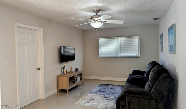 living area with visible vents, a textured ceiling, light tile patterned flooring, baseboards, and ceiling fan