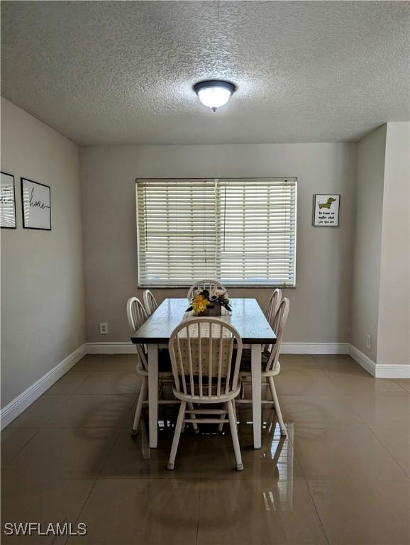 dining area featuring baseboards, a textured ceiling, and tile patterned flooring