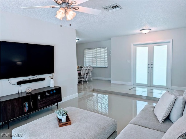 living area with a ceiling fan, baseboards, visible vents, french doors, and a textured ceiling