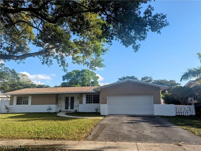 ranch-style house featuring brick siding, a front lawn, fence, french doors, and a garage