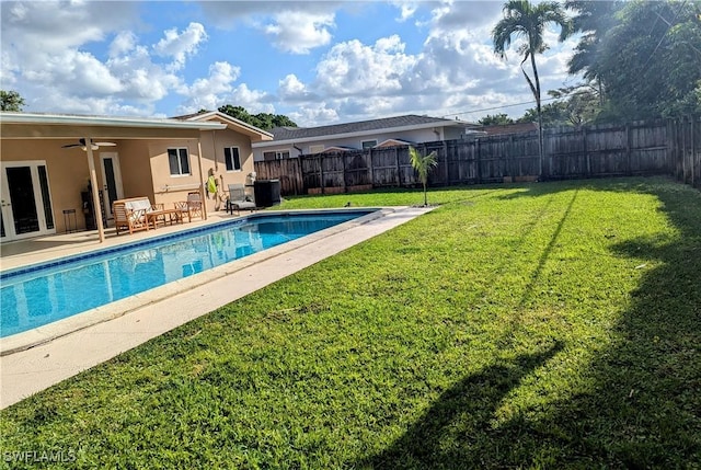 view of pool featuring a lawn, a fenced backyard, a fenced in pool, ceiling fan, and a patio area