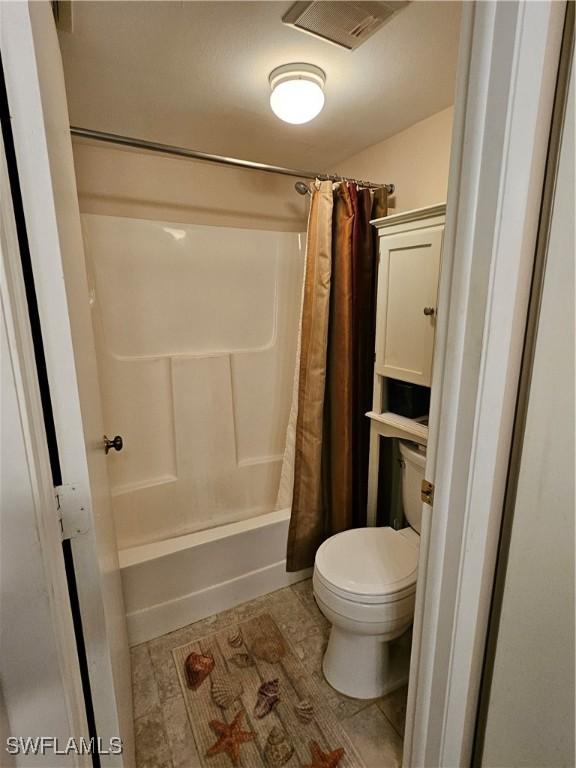 full bath with visible vents, toilet, and shower / bathtub combination with curtain