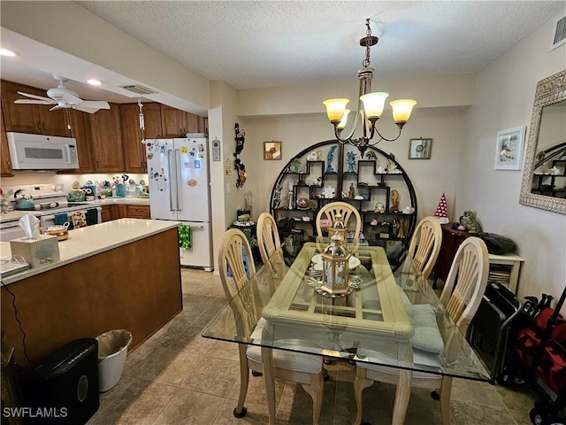 dining space featuring visible vents, a textured ceiling, light tile patterned flooring, and ceiling fan with notable chandelier