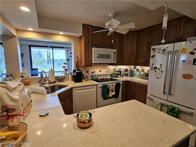 kitchen featuring white appliances, a peninsula, recessed lighting, a sink, and dark brown cabinets