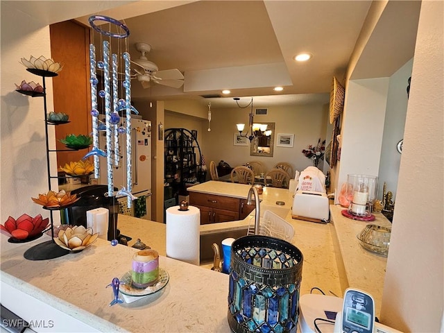 interior space with visible vents, ceiling fan with notable chandelier, high end white fridge, recessed lighting, and a raised ceiling