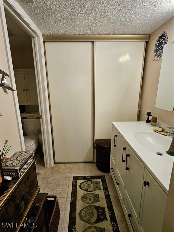 bathroom with toilet, a textured ceiling, and vanity