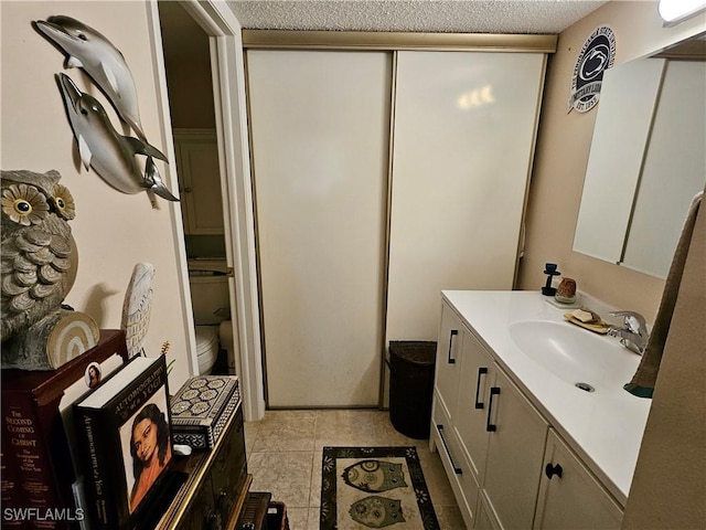 bathroom featuring toilet, a textured ceiling, and vanity