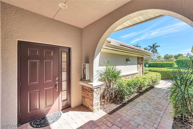 doorway to property featuring stone siding and stucco siding