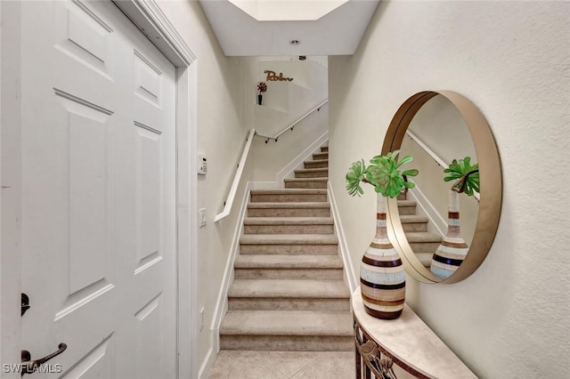 staircase featuring tile patterned floors and a skylight