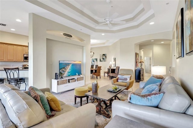 living room featuring a ceiling fan, recessed lighting, arched walkways, light tile patterned floors, and a raised ceiling